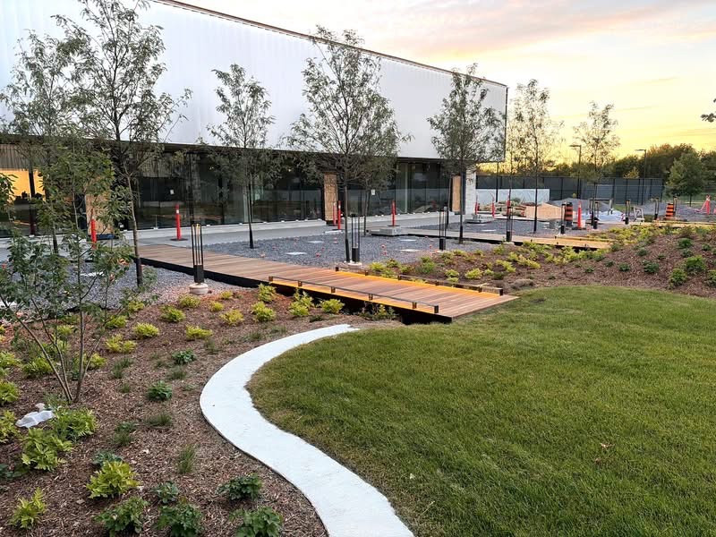 Landscaped courtyard with grass, young trees, planting beds and benches beside the complex.